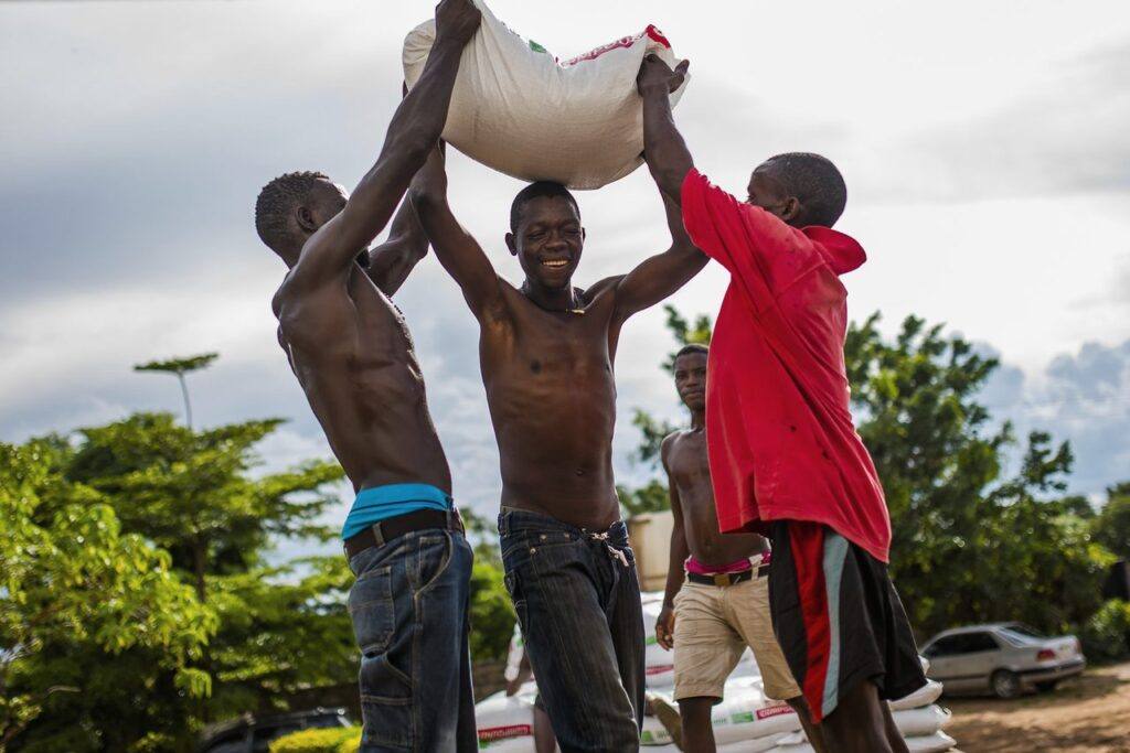 Farmers lifting a sack of seeds together